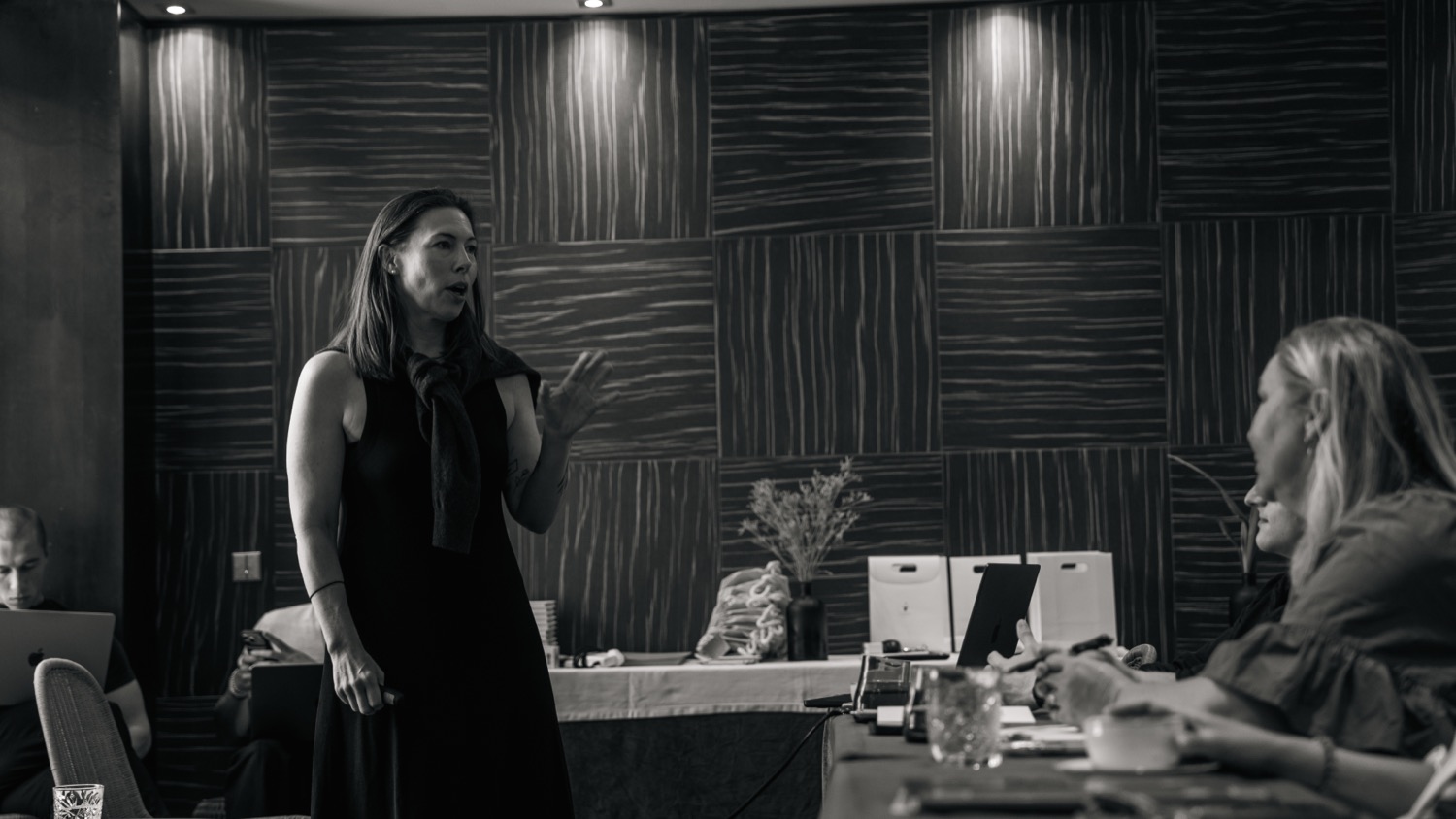 Black and white photo of a woman addressing a seated audience