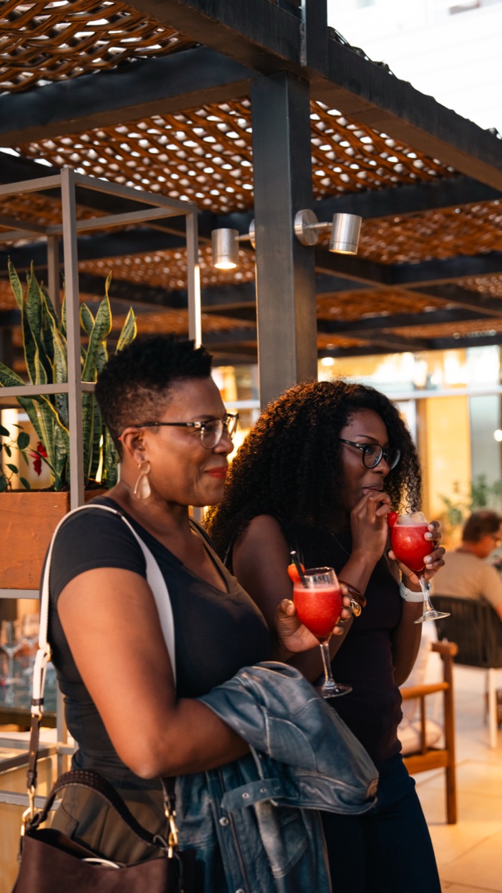 Two women talking over drinks on a terrace