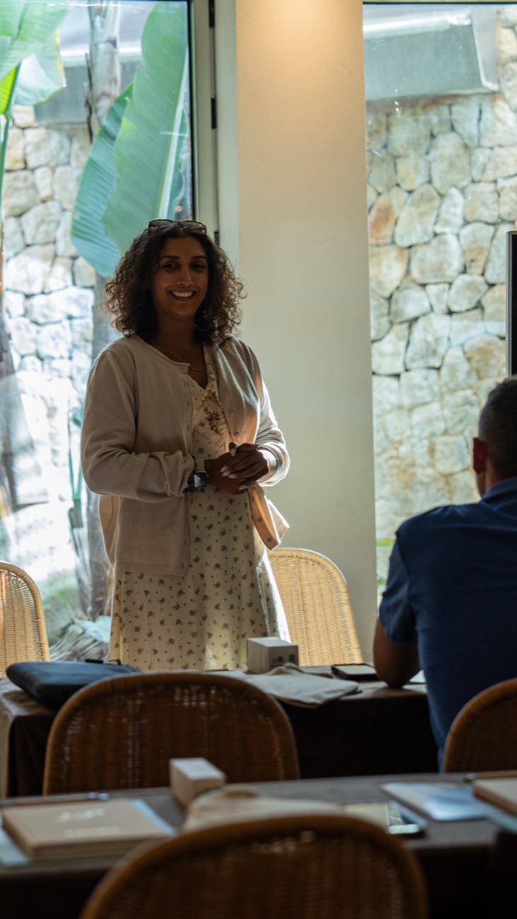 A woman speaking to the group from the front of the room